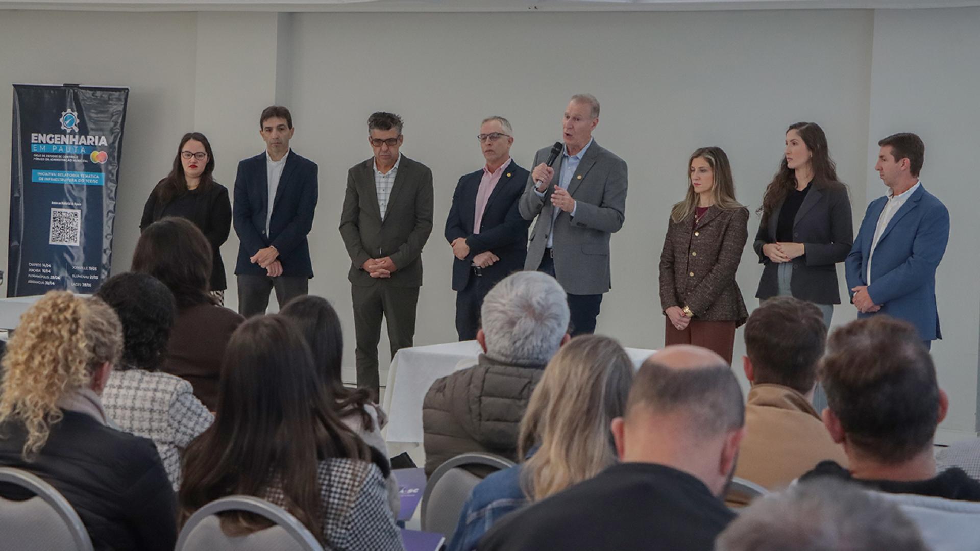 Banner horizontal com foto de integrantes do TCE/SC na abertura do evento em ambiente institucional. Há oito pessoas, lado a lado. Entre os presentes, o presidente do TCE/SC, conselheiro Herneus De Nadal, o diretor-geral de controle externo, Sidney Tavares Jr, e os diretores Rogério Loch e Marina de Miranda. 