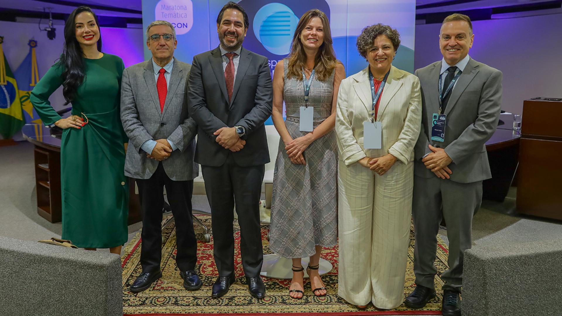 Banner horizontal com foto da conselheira substituta Sabrina Iocken e dos auditores Joseane Aparecida Corrêa e Renato Costa, do TCE/SC, entre outros participantes, durante evento institucional em Brasília, todos posicionados lado a lado em ambiente formal, com uso de crachás e vestimentas sociais, diante de painel temático ao fundo. 
