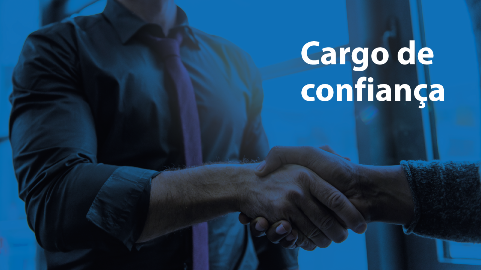 Banner horizontal com fundo em tons de azul, com efeito escurecido sobre a imagem. Ao centro, aparece o registro aproximado de um aperto de mãos entre duas pessoas. À direita, em destaque, está o texto “Cargo de confiança” em letras brancas. 
