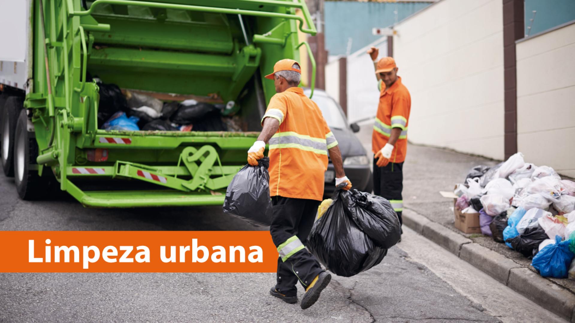 Imagem mostra dois trabalhadores da limpeza urbana realizando coleta de lixo nas ruas. Eles vestem uniforme laranja e caminham em direção a um caminhão de lixo verde. Sobre a foto, no canto inferior esquerdo, em tarja laranja, o texto “Limpeza urbana”.