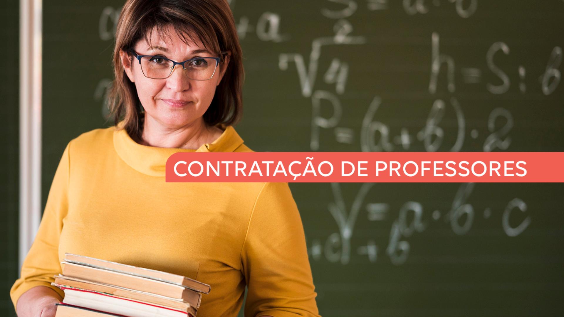 A imagem traz uma mulher à esquerda, com cabelos até curtos, castanhos escuros. Ela usa óculos e veste uma blusa laranja. É professora e segura nos braços cinco livros. Ao fundo um quadro negro com algumas palavras em giz branco. Ao centro da imagem há uma tarja vermelha onde se lê "contratação de professores"