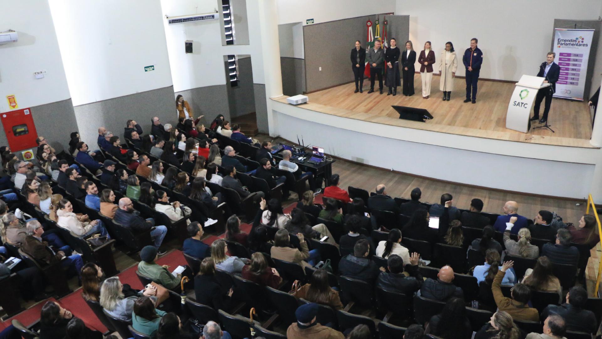 Foto feita do alto mostra pessoas em um palco e a plateia.