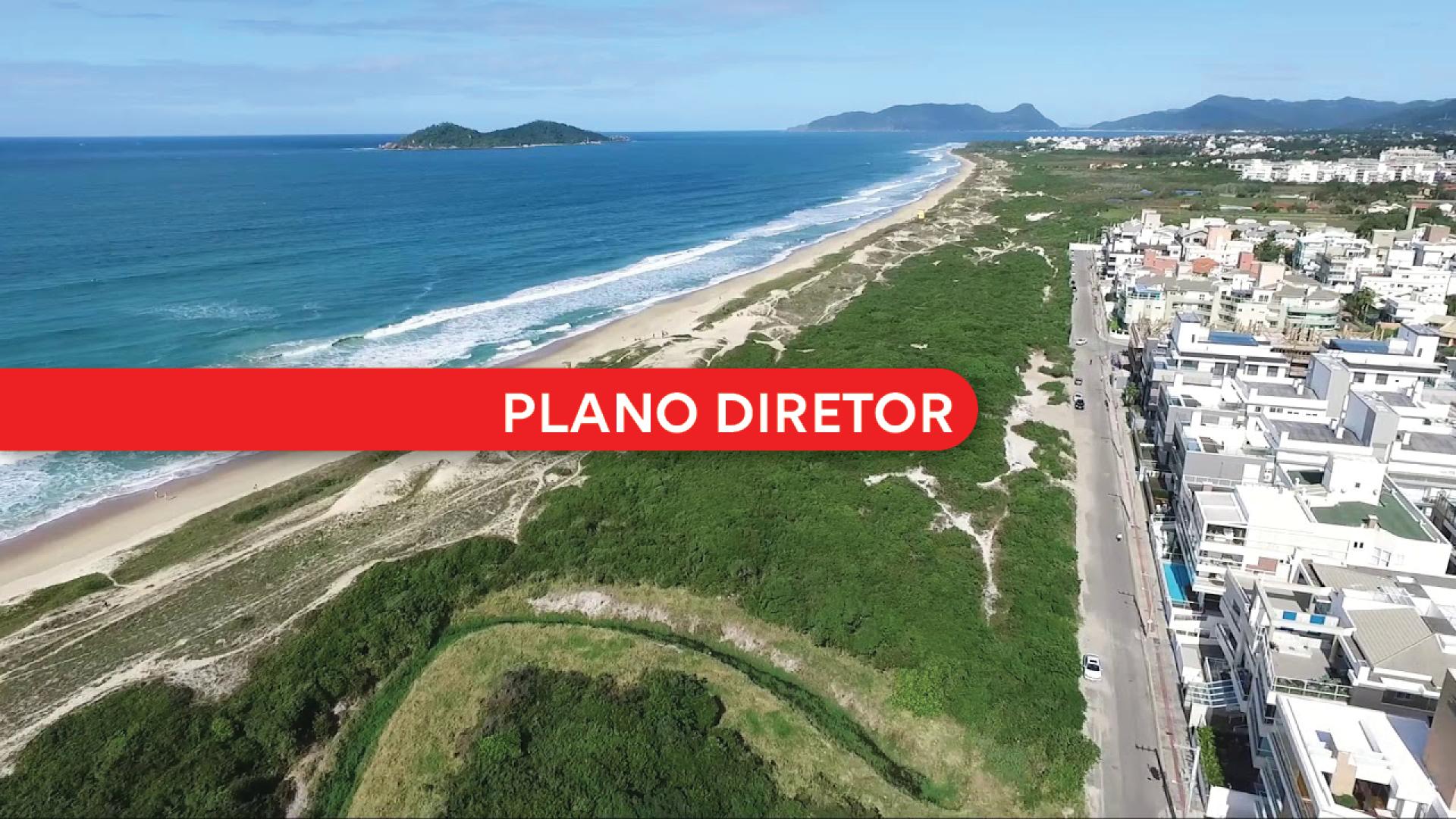 Banner horizontal com imagem aérea de uma região litorânea com extensa faixa de praia, mar azul e vegetação costeira ao longo da orla. À direita, aparecem ruas e edificações residenciais próximas ao litoral, enquanto, ao fundo, é possível ver ilhas e formações montanhosas no horizonte. Sobre a imagem, há uma faixa vermelha horizontal em destaque com o texto “Plano Diretor”, em letras brancas.