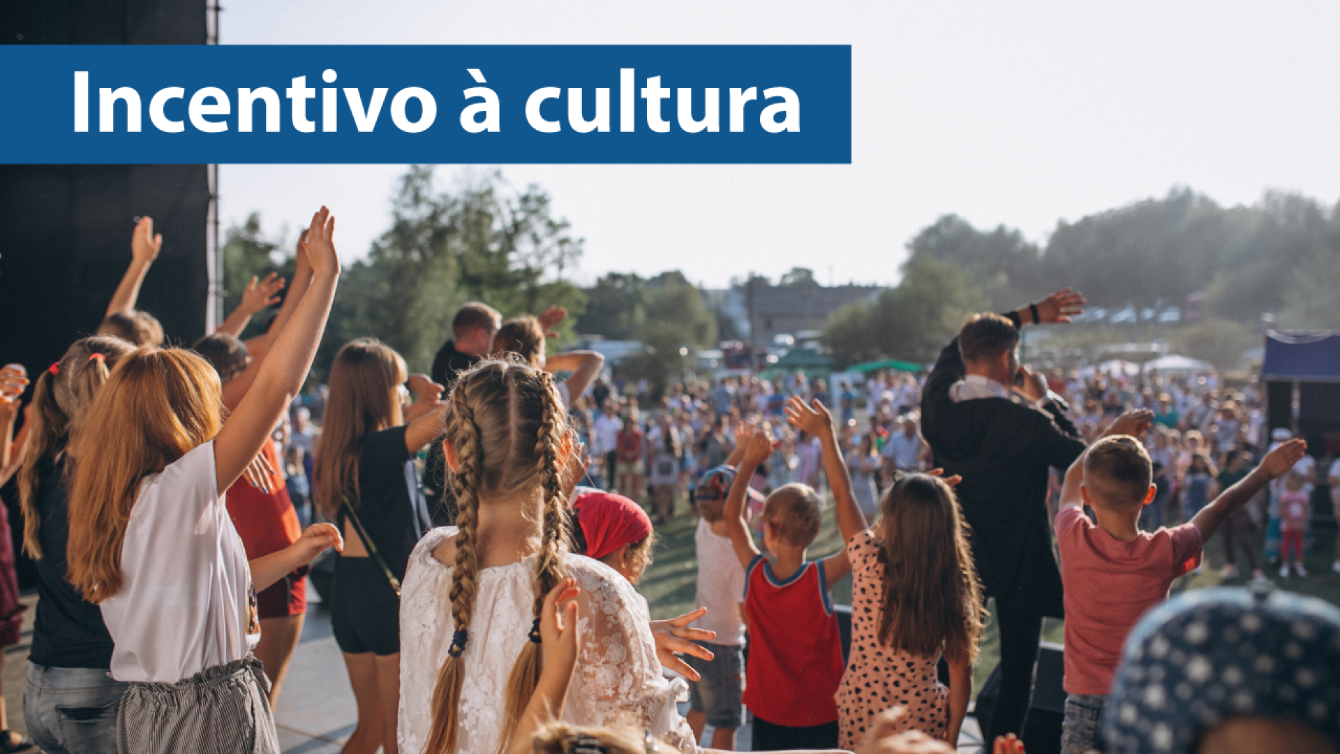 Banner horizontal com foto de várias pessoas apresentando um show, no palco. Elas erguem os braços. À frente, há pessoas que assistem, em local aberto. Sobre a foto, no canto superior esquerdo, em tarja azul, o texto “Incentivo à cultura”, em fonte branca.