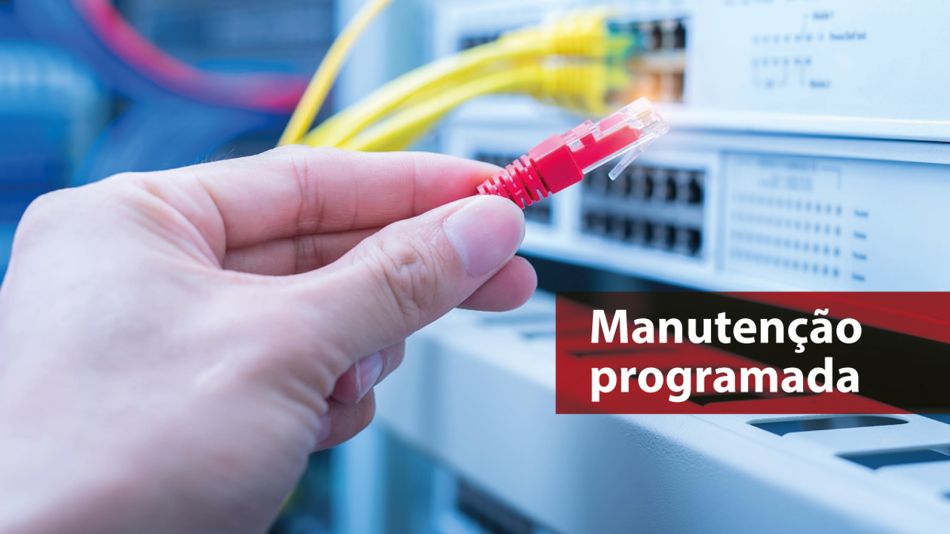 Banner horizontal com foto de uma mão segurando um cabo de rede vermelho próximo a um painel de rede. Sobre a foto, à direita, em tarja bordô, o texto “Manutenção programada”. 