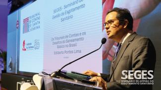 Foto do presidente do IRB, conselheiro Edilberto Pontes Lima, proferindo palestra. Ao fundo, projeção do da sua apresentação no telão. No canto inferior direito, o logo do Seges. 