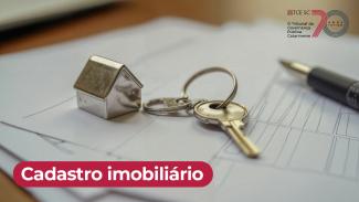Imagem mostra um chaveiro sobre papéis que estão em uma mesa. Na parte inferior, à esquerda, em branco sobre uma tarja preta, está escrito Cadastro Imobiliário
