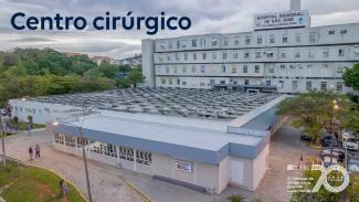 Imagem mostra a fachada do hospital, de cor predominantemente branca. No alto, às esquerda, está escrito Centro Cirúrgico