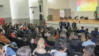 Banner horizontal com foto da abertura da etapa de Criciúma do Ciclo de Estudos. Em primeiro plano, a plateia, de costas, sentada em poltronas do auditório, que assiste à fala do vice-presidente do TCE/SC, conselheiro Ascari, que está à frente, junto com outros membros do Tribunal. Entre eles, o diretor do Icon, Moisés Hoegenn.     