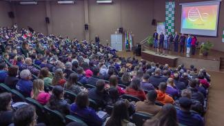 Foto do auditório lotado durante uma das etapas do Ciclo de Estudos. O público está de costas, sentado em poltronas. À frente, no palco, membros do TCE/SC falam durante a abertura.