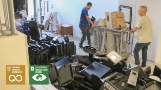 Banner horizontal com foto de dois homens carregando, em uma estrutura de ferro, móveis, eletrodomésticos e equipamentos de informática fora de condições de uso. Ao lado deles, há uma pilha de equipamentos eletrônicos para descarte. Sobre a imagem, no canto inferior esquerdo, os ícones dos Objetivos de Desenvolvimento Sustentável 12, consumo e produção responsáveis, e 13, ação contra a mudança global do clima. 