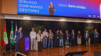 Foto mostra um grupo de pessoas sobre um palco.