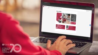 Banner horizontal com foto que mostra uma pessoa utilizando um notebook, com as mãos sobre o teclado, acessando uma plataforma digital exibida na tela. O site apresenta a interface do “Educa TCE/SC”, com cards de cursos e conteúdos relacionados à capacitação na área pública. No canto inferior esquerdo, logo do TCE/SC.