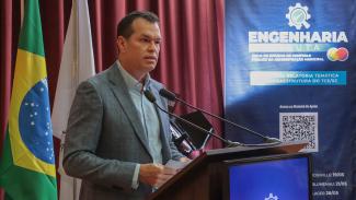 Banner horizontal com foto do conselheiro-corregedor, Adircélio de Moraes Ferreira Júnior, falando ao púlpito, no auditório do TCE/SC. Ele é um homem branco, de cabelos escuros. Veste paletó cinza. Ao seu lado, banner vertical com logo do Engenharia em Pauta. Ao fundo, cortinas bordôs.