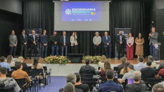 Banner horizontal com foto da equipe do TCE/SC no palco do auditório em Araranguá. Entre os presentes, o presidente, Herneus De Nadal, que fala ao microfone, diretores e auditores. Todos estão lado a lado. Atrás, no telão, é exibido o logo do Engenharia em Pauta. À frente deles, de costas para a foto, a plateia que acompanha a fala do presidente.