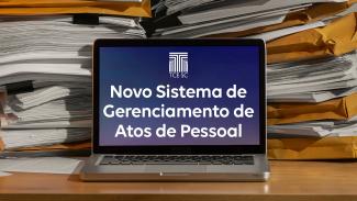 Imagem mostra um laptop aberto sobre uma mesa. Na tela, aparece escrito “Novo sistema de Gerenciamento de Atos de Pessoal”, em fundo azulado e letras brancas. Atrás do computados há uma pilha de folhas e envelopes