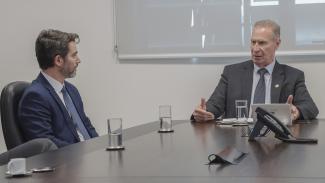 Banner horizontal com foto de reunião institucional. Aparecem, lado a lado, o presidente do TCE/SC, conselheiro Herneus De Nadal, e o procurador-geral do Estado, Marcelo Mendes. Herneus gesticula enquanto fala. Sobre a mesa, há copos de água. 