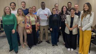 Foto dos participantes do terceiro módulo do curso reunidos, um ao lado do outro, em pé, em uma sala de aula, no TCE/SC. Há 14 pessoas. Ao centro, o professor Delton Felipe, que segura o certificado recebido. Ao lado dele, a integrante da CPFAR Walkiria Machado Rodrigues Maciel. 