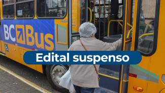 Imagem tem como fundo um ôninus amarelo escrito BC Bus na lateral. Há uma mulher de cabelo grisalho entrando pela porta da frente. Ao centro está escrito Edital Suspenso, em letras brancas sobre uma tarja azul. 