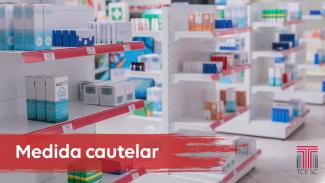 Banner horizontal com a imagem de diversas prateleiras com caixas de remédio. No canto inferior esquerdo, há inscrito em branco sobre fundo vermelho "Medida cautelar”. No canto inferior direito está a logomarca do Tribunal de Contas. 