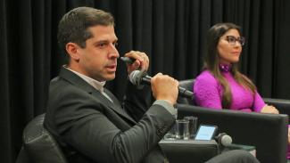 Foto horizontal com o líder de Infraestrutura e Mercados Regulados para a América Latina, Diogo Mac Cord de Faria, em primeiro plano, e com a presidente da Comissão de Desenvolvimento e Infraestrutura da OAB/SC, Marcela Felício. Ambos estão sentados em poltronas. 