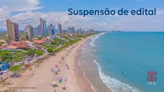 Foto aérea de uma praia da cidade de Balneário Piçarras. À esquerda da foto aparece parte da cidade com prédios, casas, ruas e árvores; ao centro a faixa de areia, com vários guarda-sóis e banhistas; e à direita, o mar. Sobre a foto, no canto superior direito há o título “Suspensão de edital”, e no canto inferior direito, a logo do TCE/SC. No canto inferior esquerdo, em fonte bem pequena, há a identificação do crédito da foto, com o texto “Foto: Prefeitura de Balneário Piçarras”.