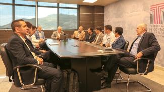 Foto de onze pessoas sentadas ao redor de uma mesa na sede do TCE/SC, enquanto conversam. Entre os presentes, integrantes do TCE paranaense e membros do TCE/SC. Entre eles, o diretor Nilsom Zanatto.