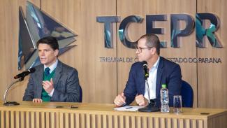Banner horizontal com foto do diretor Nilsom Zanatto, do TCE/SC, ao lado do presidente do TCE/PR, conselheiro Ivens Linhares. Eles estão sentados diante de uma bancada, falando ao microfone. Ambos vestem paletó. Ao fundo, na parede, logo do Tribunal de Contas do Paraná.