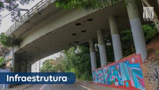    Imagem mostra um viaduto. À esquerda, sobre tarja azul e em letras brancas, há a inscrição “Infraestrutura”. À direita, aparecem quatro pilares e há pintura colorida em um muro. No alto, à direita, há a logo do Tribunal em branco