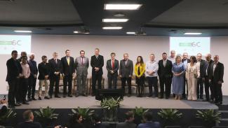 Foto das autoridades no palco do auditório do TCE/SC, durante reunião do Comitê Gestor do Acerta SC. Há 21 pessoas em pé, uma ao lado da outra. Entre os presentes, os presidentes Herneus De Nadal e Francisco Oliveira Neto, os conselheiros Aderson Flores, Adircélio de Moraes e José Nei Ascari e a procuradora-geral adjunta Cibelly Farias.