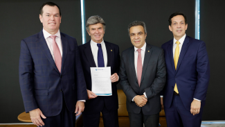 Foto de quatro homens, um ao lado do outro, em pé. São eles: conselheiro Adircélio de Moraes Ferreira Júnior, conselheiro Edilson Silva, ministro Mauro Campbell e ministro Luiz Fux. Todos vestem terno e gravata e sorriem. O ministro Campbell segura e mostra uma folha de papel para a foto.