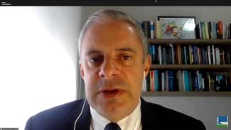 Foto do conselheiro substituto Gerson Sicca durante audiência pública on-line. Sua imagem, cortada do tronco para cima, ocupa a tela inteira. Ele é um homem branco, de cabelos grisalhos. Veste terno e gravata e usa fones de ouvido. 