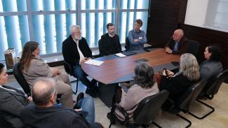 Foto de dez pessoas sentadas ao redor de uma mesa durante reunião entre o TCE/SC, TJSC e a UFSC, enquanto conversam. Entre os presentes, o conselheiro Luiz Eduardo Cherem, o juiz auxiliar Rafael Sandi e a coordenadora do Núcleo de Telessaúde da UFSC, Maria Cristina Calvo.