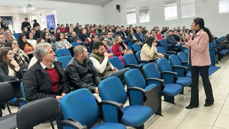Foto da palestra da diretora de Atos de Pessoal, Ana Paula Machado Costa (em pé) e dos participantes (sentados em cadeiras azuis) 