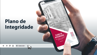 Descrição da imagem: Banner em tons de branco e cinza. Na lateral direita, uma mão branca segura um celular. Na tela do celular, há a imagem das sedes do TCE/SC em preto e branco e o título “Plano de Integridade” em um fundo vermelho. Na lateral esquerda, há o texto “Plano de Integridade” em fonte preta. Mais abaixo, há uma barra de pesquisa com os ícones de voltar, avançar, atualizar e home. Ao lado, o texto “tcesc.tc.br” 