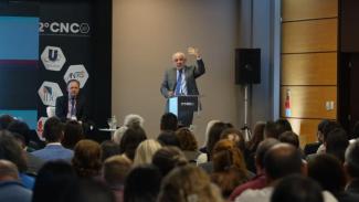 Foto do conselheiro Luiz Eduardo Cherem proferindo palestra para a plateia formada por homens e mulheres