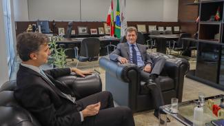 Foto do presidente em exercício do TCE/SC, conselheiro José Nei Ascari, e o presidente da Fecam e prefeito de Gaspar, Kleber Wan-Dall, estão sentados na sala da presidência do TCE/SC. À esquerda da foto está o presidente da Fecam e do lado direito o conselheiro Nei. Ambos os homens brancos vestindo ternos escuros.  