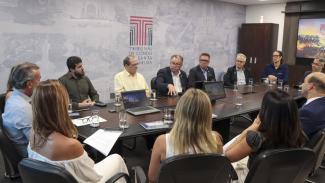 Foto da reunião entre integrantes do TCE/SC e representantes de diversas entidades ligadas ao setor da infraestrutura do estado. As 14 pessoas estão sentadas ao redor da mesa da sala de reuniões da presidência do TCE/SC.