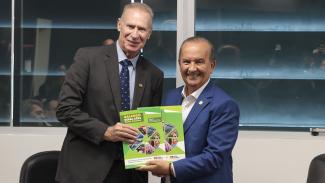 Banner horizontal com foto do presidente do TCE/SC, Herneus De Nadal, ao lado do governador Jorginho Mello, em um ambiente institucional. Ambos estão em pé, sorrindo, enquanto seguram juntos o relatório “Balanço Geral 2025 – Santa Catarina”. A cena registra o momento de entrega das contas do governo estadual ao Tribunal de Contas.