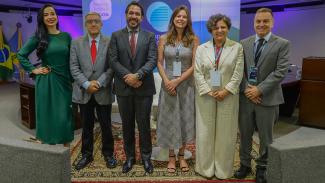 Banner horizontal com foto da conselheira substituta Sabrina Iocken e dos auditores Joseane Aparecida Corrêa e Renato Costa, do TCE/SC, entre outros participantes, durante evento institucional em Brasília, todos posicionados lado a lado em ambiente formal, com uso de crachás e vestimentas sociais, diante de painel temático ao fundo. 