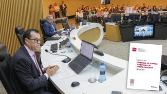 Foto da sessão do Pleno. Em primeiro plano, à esquerda, o conselheiro Adircélio de Moraes Ferreira Júnior, que está sentado. À direita, a capa da RTCE/SC. Ao fundo o conselheiro Aderson Flores e o público. 