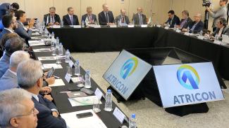 Foto da sala onde aconteceu a reunião. As mesas estão dispostas em formato de U, e ao centro, quatro monitores de televisão, voltados para cada lado da formação de mesas. Sentadas, estão várias pessoas, entre membros da diretoria da Atricon e conselheiros convidados. O presidente do TCE/SC, Herneus de Nadal, aparece ao lado do presidente da Atricon, Edilson Silva, e do conselheiro Cesar Miola. Entre outros conselheiros aparece o conselheiro do TCE/SC, Wilson Wan-Dall. 