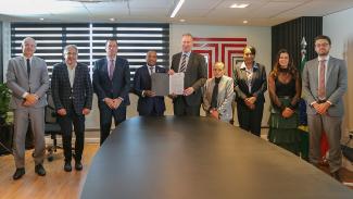 Foto horizontal com os participantes do ato de assinatura do acordo de cooperação técnica, entre integrantes do TCE/SC, do TC de Angola e do MPTC/SC. Todos estão em pé. Ao centro e segurando o documento, os presidentes dos dois tribunais, Sebastião Gunza e Herneus De Nadal (da esquerda para a direita). 