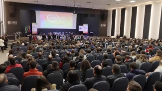 Foto de um auditório cheio. Em frente ao público diversas autoridades, entre elas o presidente do TCE/SC, conselheiro Herneus De Nadal. Ao fundo, no palco, uma grande projeção da logomarca do Ciclo de Estudos.