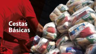 Imagem com pilha de cestas básicas embaladas, prontas para distribuição, ao lado de uma pessoa manuseando uma delas. 