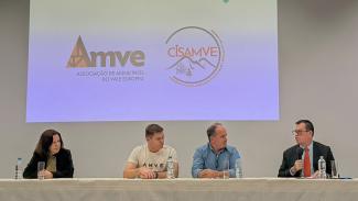 Foto horizontal da mesa composta do evento. À esquerda, o conselheiro e Corregedor-Geral do TCE/SC Adircélio de Moraes Ferreira Júnior. Ao lado outras 3 pessoas - 2 homens e uma mulher. Ao fundo projetada a logomarca da AMVE.