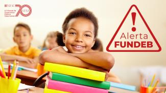 Banner de um menino debruçado sobre uma pilha de livros, sorrindo. Ele está em uma sala de aula. Sobre a foto, à direita, o texto “Alerta Fundeb”, dentro de um ícone de atenção. No canto superior esquerdo, selo comemorativo aos 70 anos do TCE/SC.