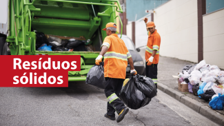 Banner horizontal com foto de dois trabalhadores, que vestem uniforme laranja, coletando o lixo em uma rua e o levando em direção ao caminhão estacionado. Sobre a imagem, à esquerda, em tarja vermelha, o texto “Resíduos sólidos”. 