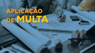 Banner horizontal com foto com tonalidade azulada mostrando uma mesa de trabalho coberta por plantas e projetos de engenharia. Ao centro, uma pessoa faz anotações sobre os documentos com uma caneta. Sobre a imagem, o título "Aplicação de multa". 