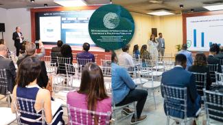 Banner horizontal dividido ao meio. À esquerda, foto, do conselheiro substituto Gerson dos Santos Sicca falando ao público durante o evento. Ele está em pé, próximo ao telão que projeta sua apresentação. À sua frente, há pessoas sentadas em cadeiras, assistindo à fala do conselheiro. À direita, os servidores Elisete Da Correggio e Mateus Galindo falando ao público durante o evento. Eles estão em pé, em frente ao público, que está sentado em cadeiras. 